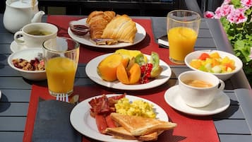 A breakfast table with various dishes including croissants, fruit, toast, and beverages.