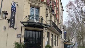 La façade d’un hôtel, avec une grande entrée, un balcon orné de balustrades en fer forgé, et une enseigne indiquant qu’il s’agit d’un hôtel Best Western.