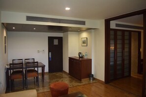 A room with a dining table and chairs, a small cabinet, a door, and a traditional sliding door. - Centurion Hotel (Pune)