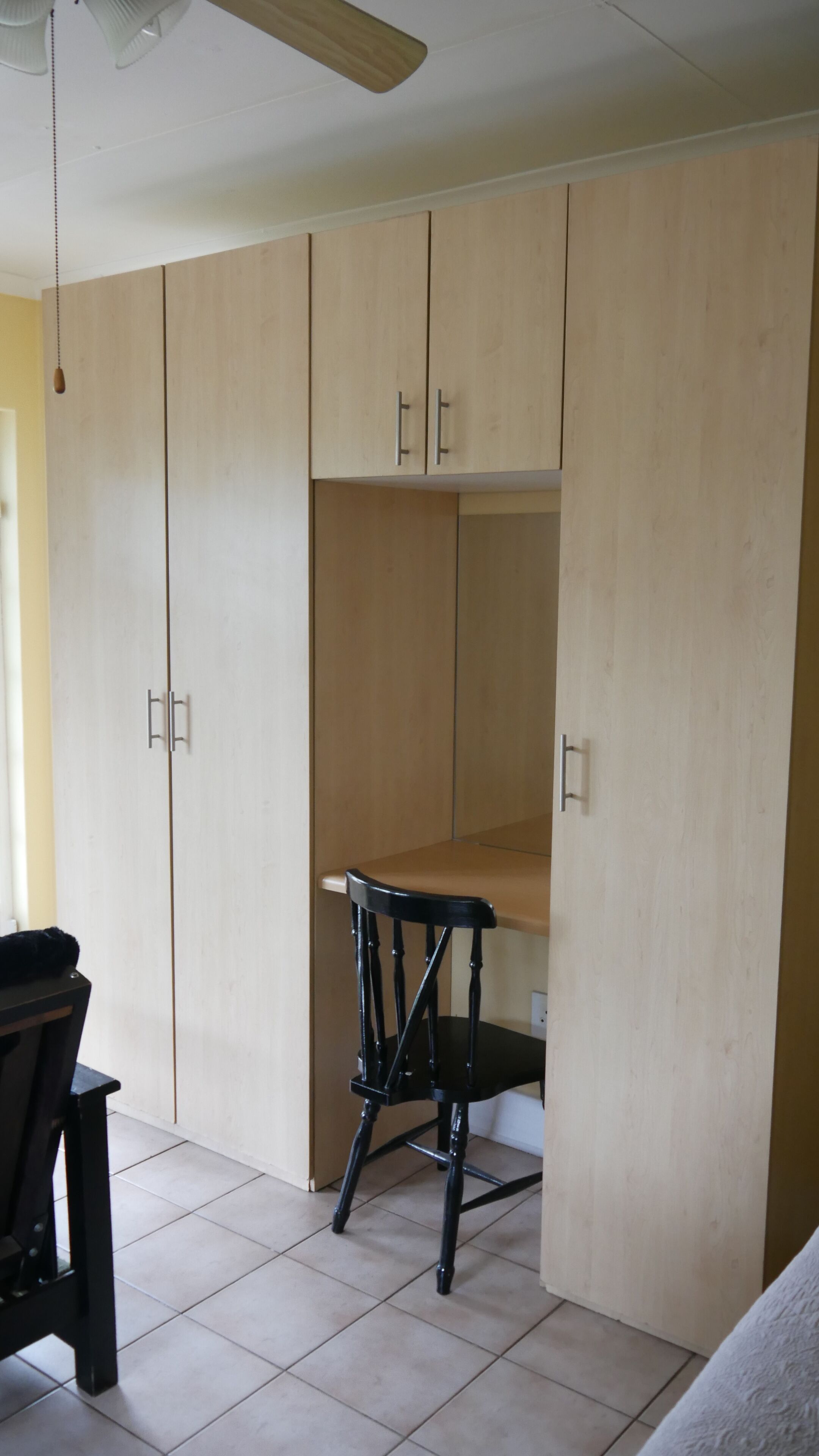 Una habitación con un armario de madera, una mesita y una silla.