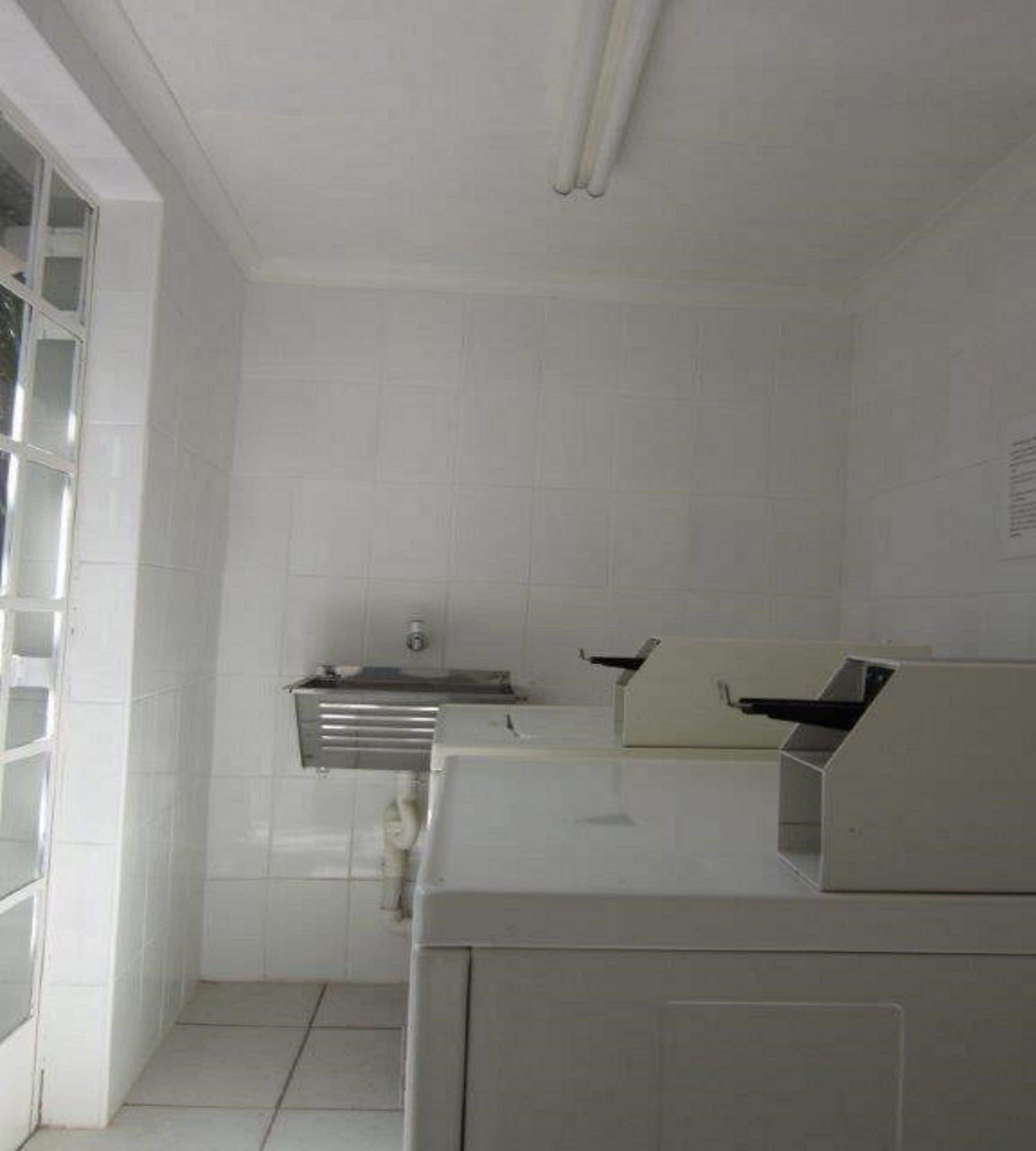 Una cocina con azulejos blancos, un lavamanos de acero inoxidable y un horno empotrado.
