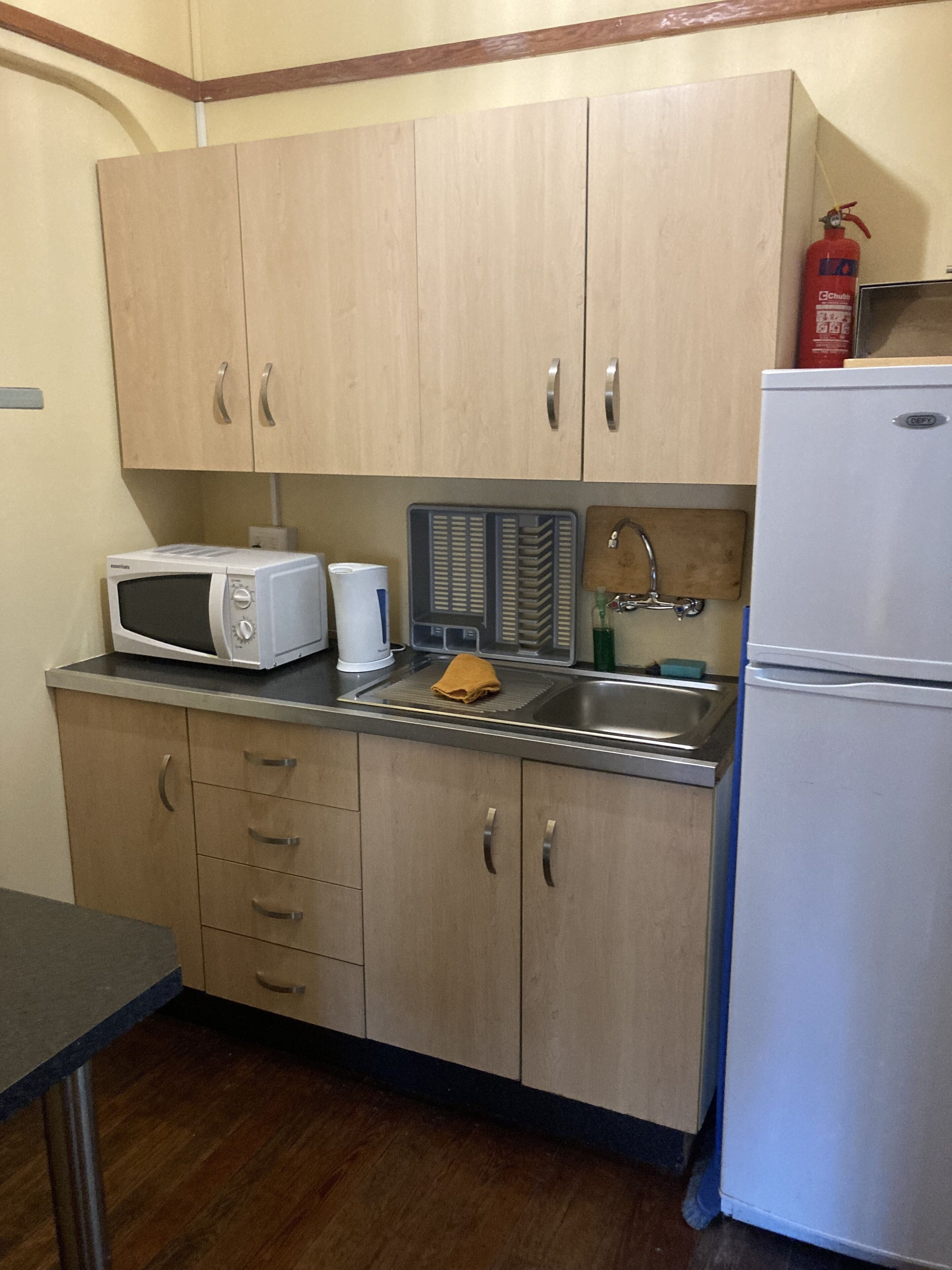 A kitchen with wooden cabinets, a microwave, a sink, and a refrigerator.
