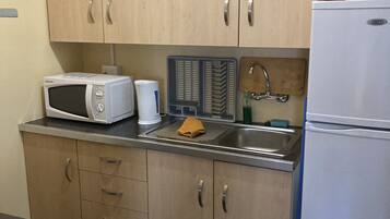 A kitchen with wooden cabinets, a microwave, a sink, and a refrigerator.