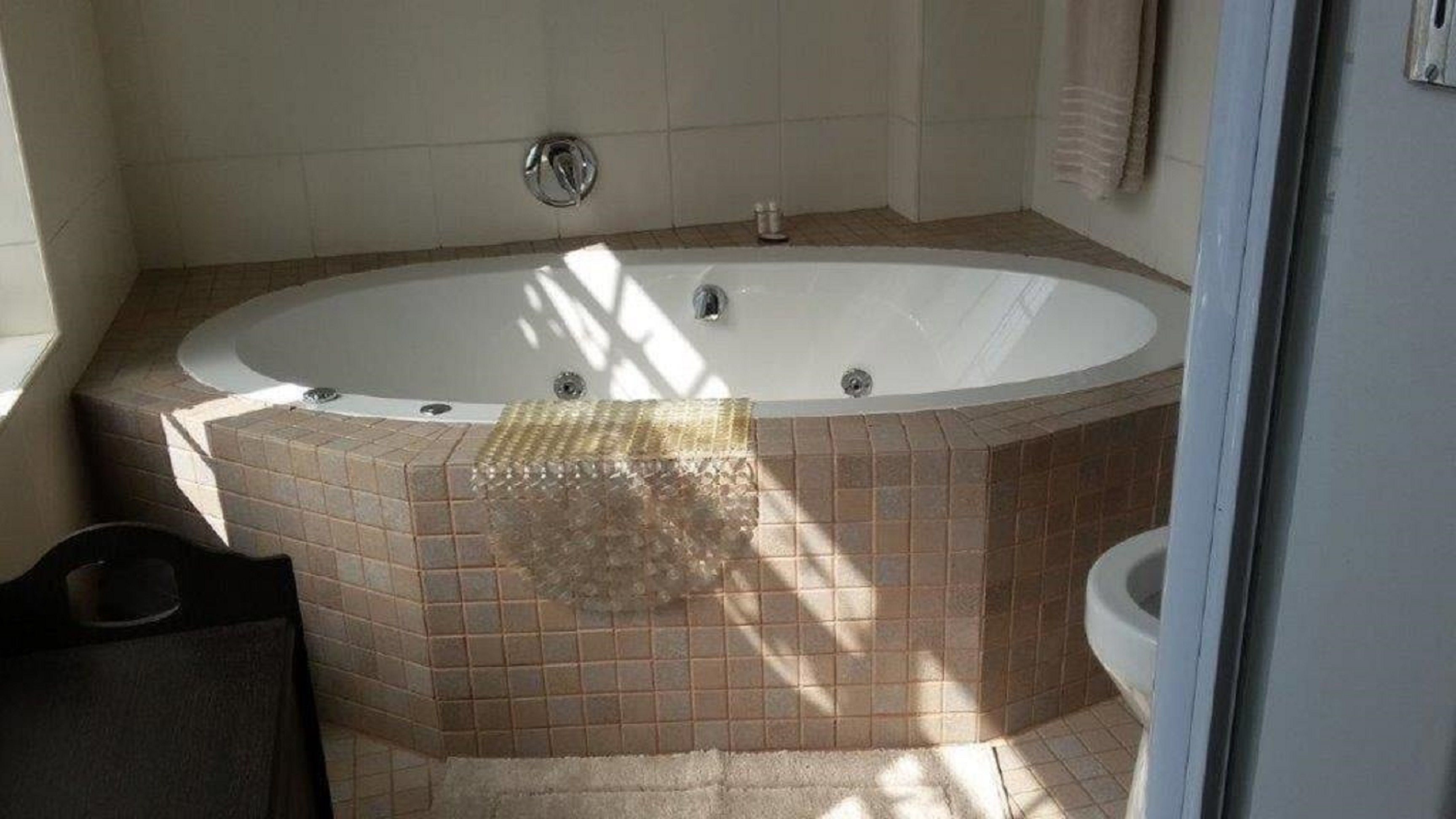 Une salle de bain dotée d’une grande baignoire ovale, de murs carrelés et d’un espace douche.