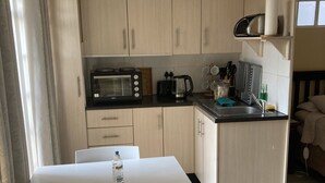 Een compacte keuken met een eethoek, met daarin een magnetron, broodrooster en waterkoker.