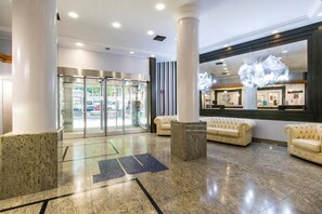 A lobby with a glass door entrance, marble flooring, and a reception desk with a modern light fixture. - Hotel Turin Royal (Turin)