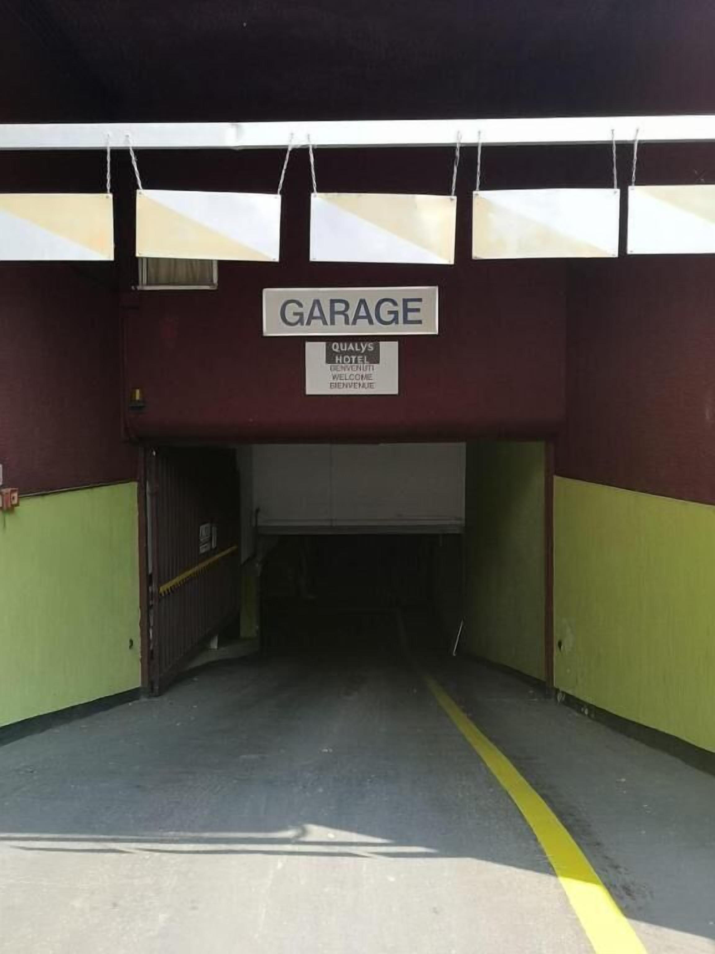 A garage entrance with a sign indicating it is part of Qualys Hotel.