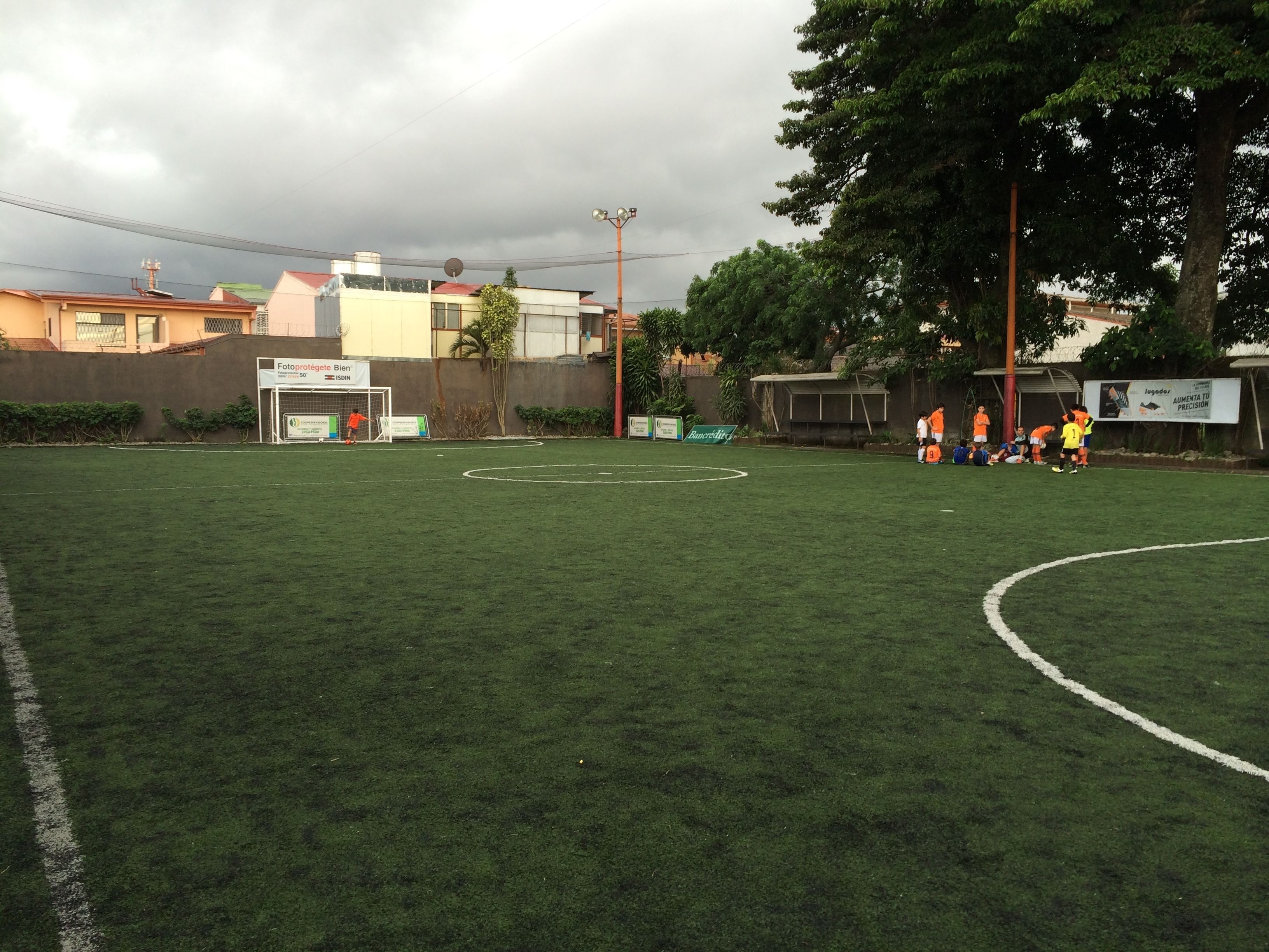 Un campo de fútbol con porterías, un anuncio en la banda lateral y un edificio al fondo.