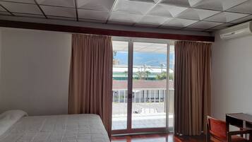 A hotel room with a bed, a desk, and a view of the outside.
