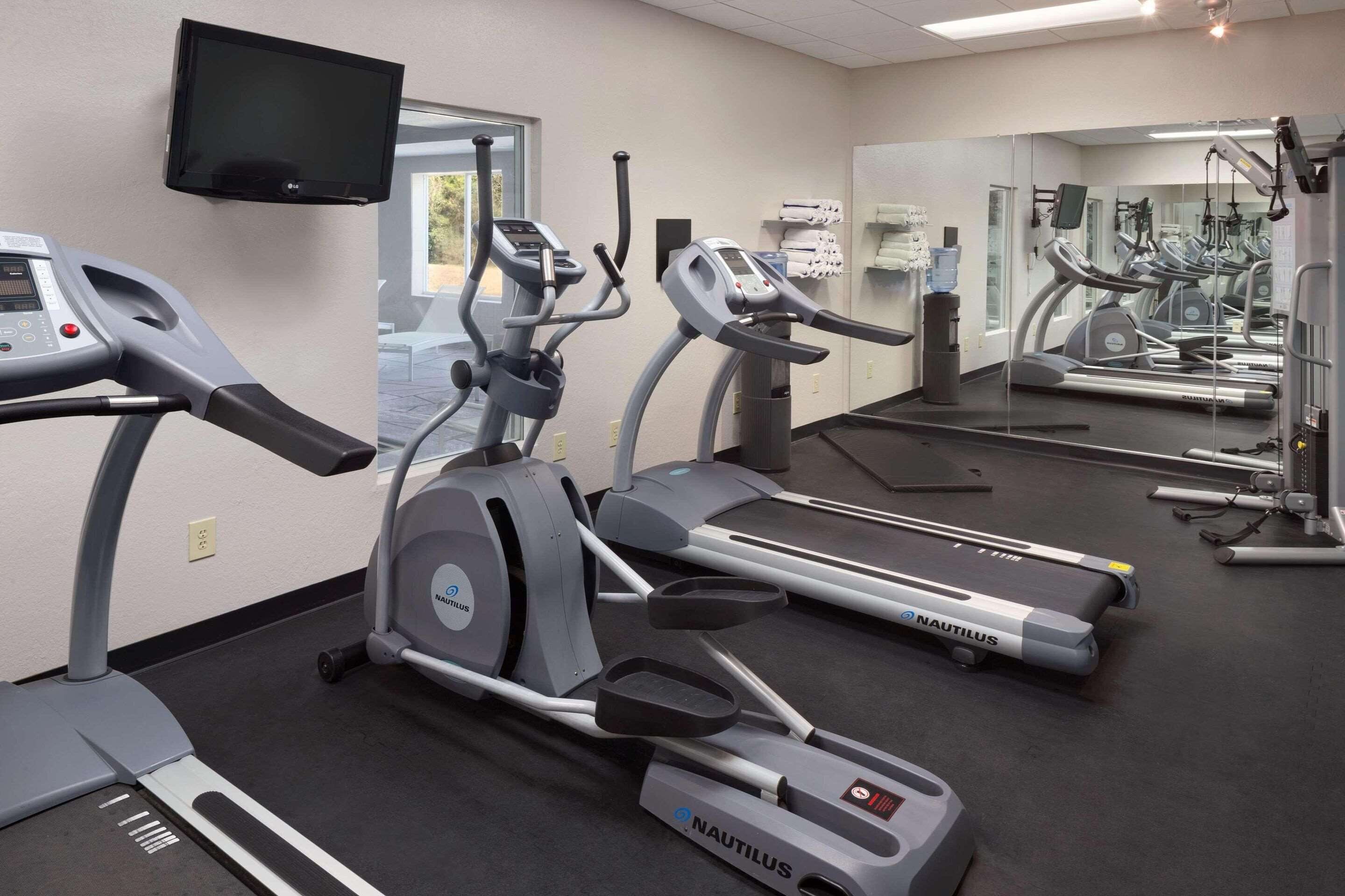 A gym with Nautilus treadmills, a TV, and a large mirror.