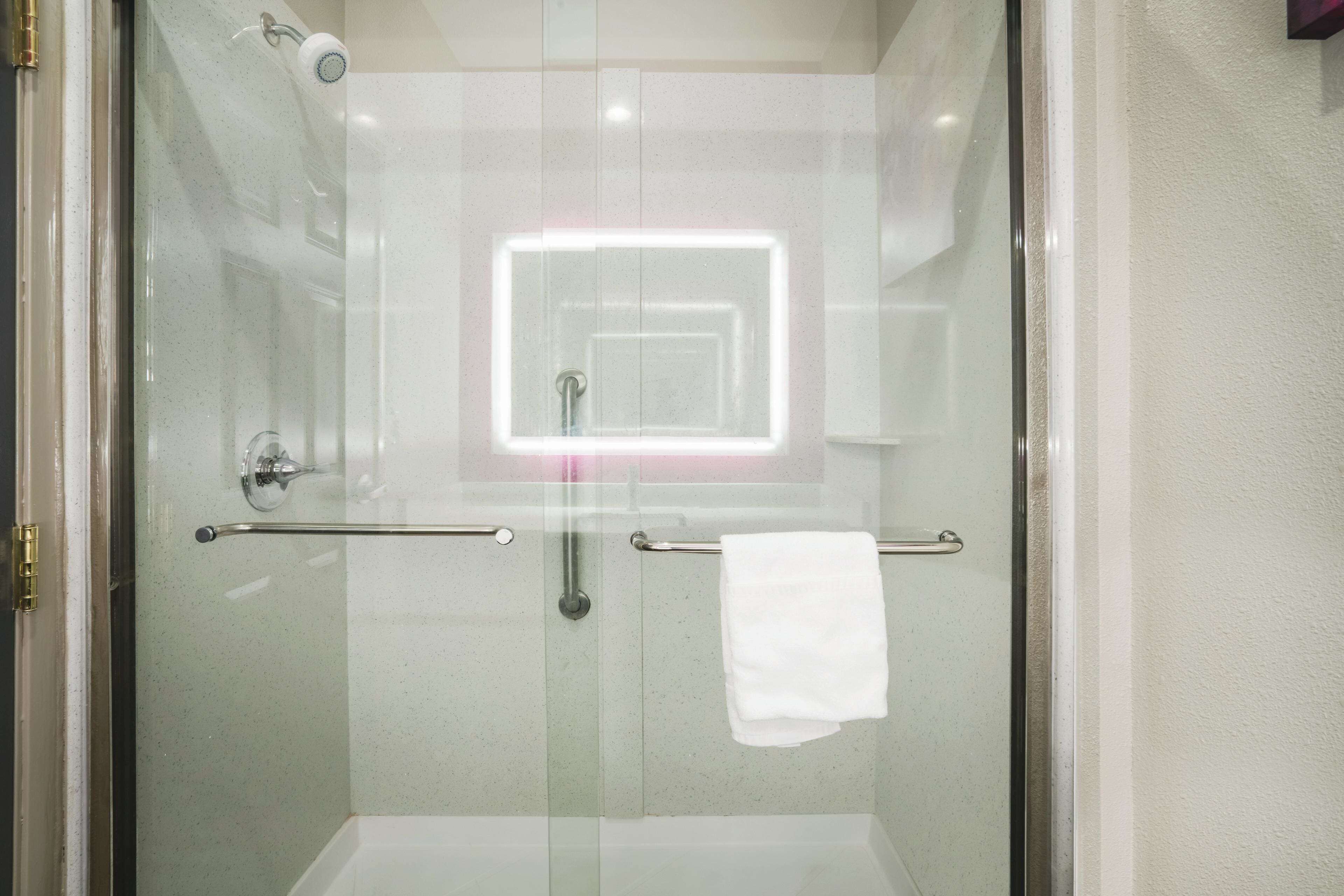 Una cabina doccia in vetro con ringhiera a vista e porta asciugamani.