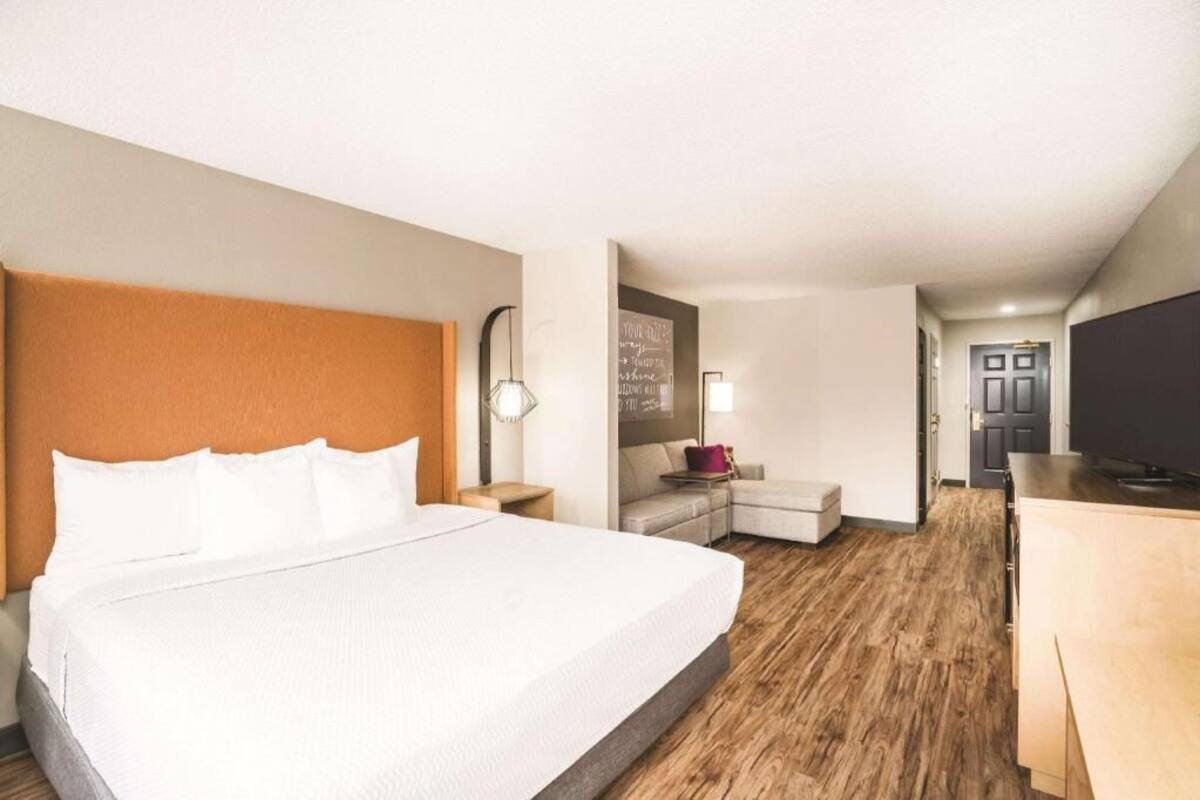 Ein Hotelzimmer mit einem großen Bett, einem Schreibtisch, einem Fernseher und einer kleinen Sitzecke.