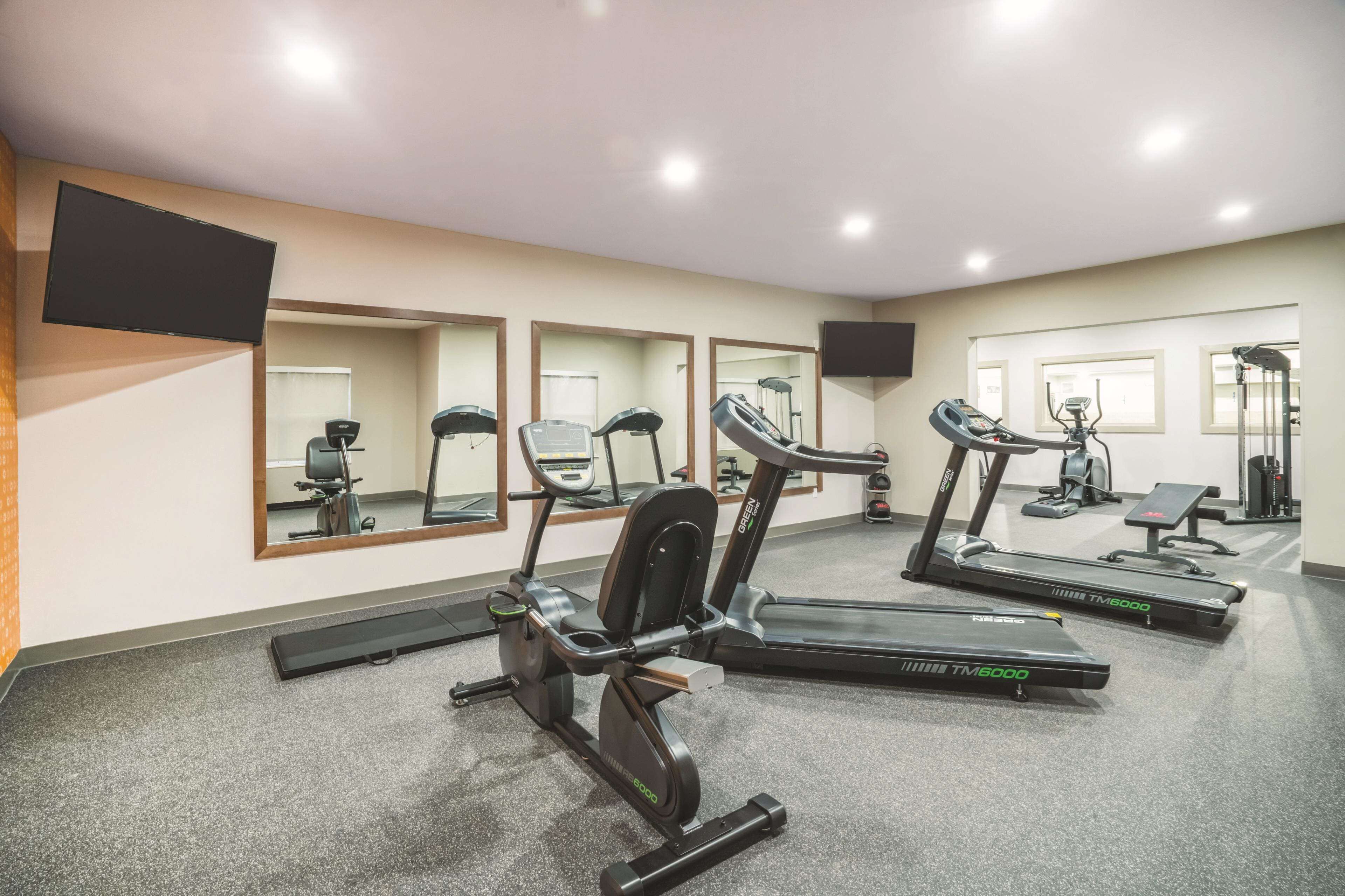 Un gimnasio con cintas de correr, elípticas y un muro de espejos.