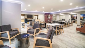 Un vaste espace intérieur aménagé avec différents coins salon, comprenant des canapés et des fauteuils, ainsi qu’un coin repas avec des tables et des chaises.
