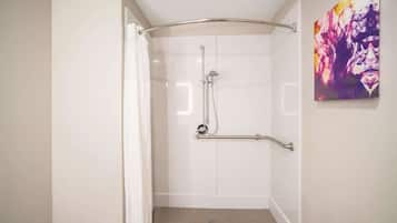 Une douche à l’italienne avec une barre d’appui, un rideau blanc et un sol carrelé.