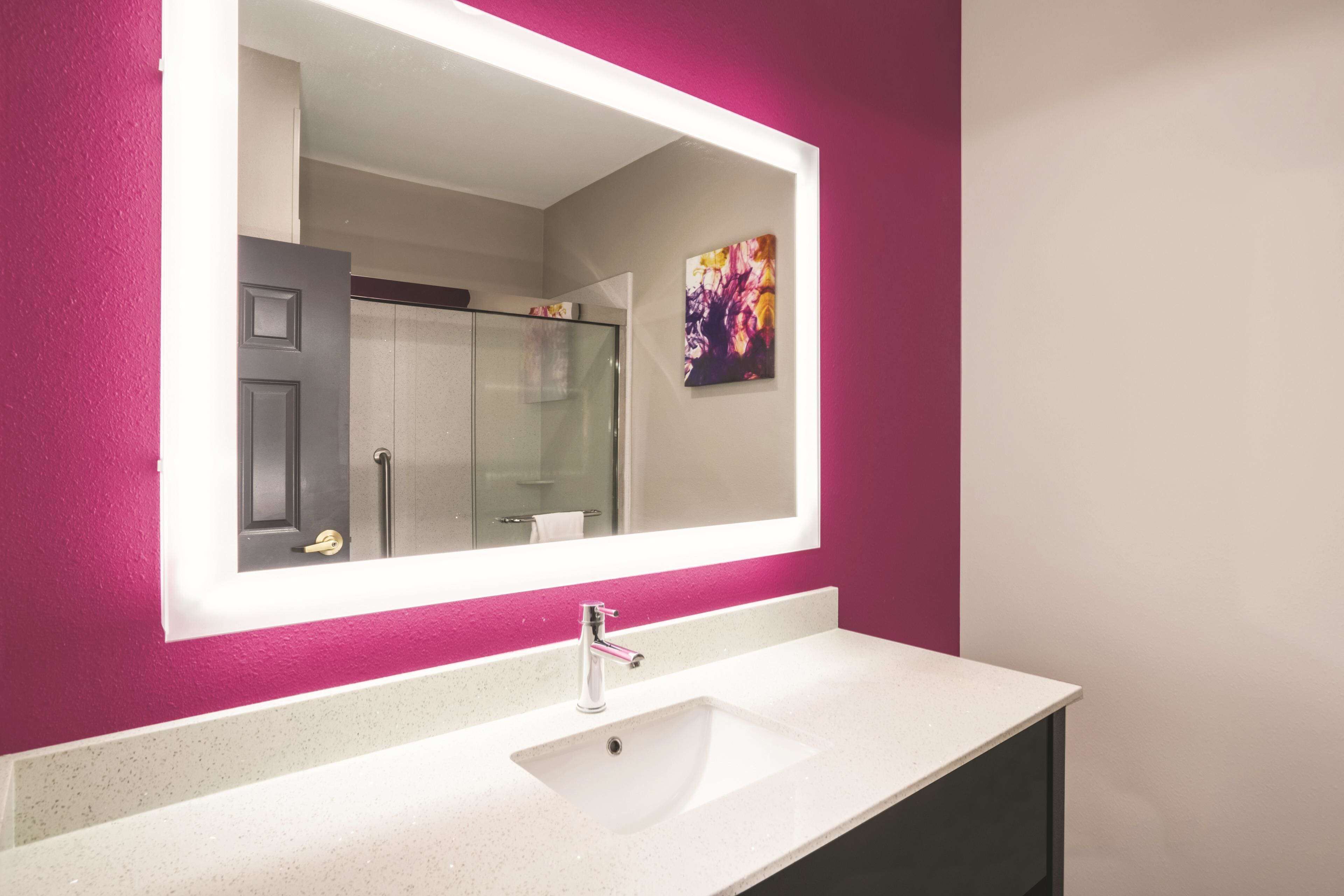 Une salle de bain avec un lavabo blanc, un grand miroir et une douche en verre.