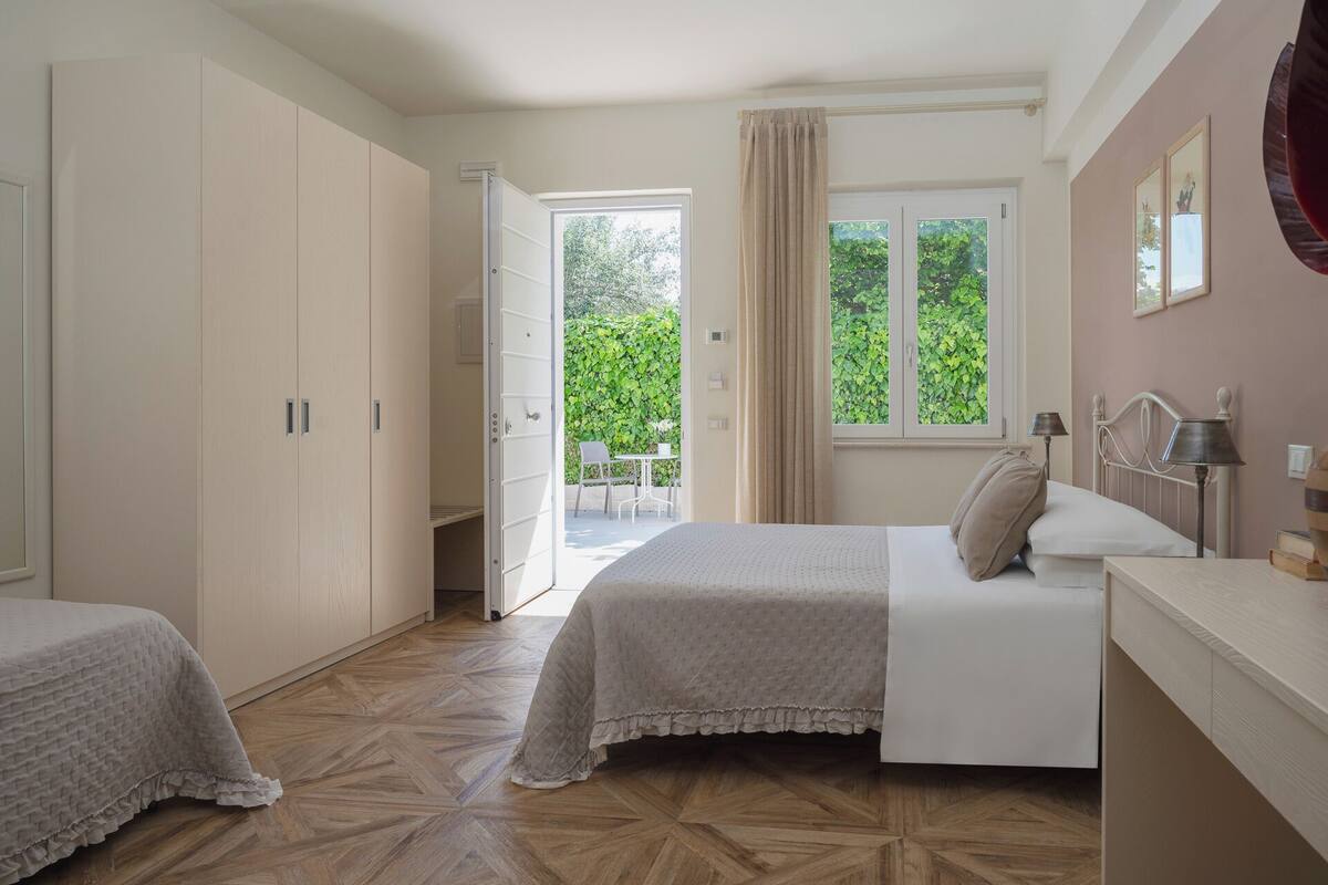 A bedroom with a bed, bedside table, and a window with curtains.