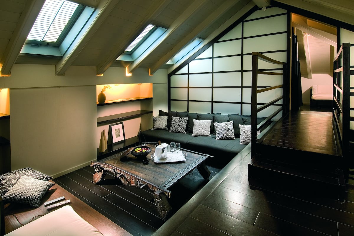 A loft-style living area with a sofa, a coffee table, and a view of the sky through skylights.
