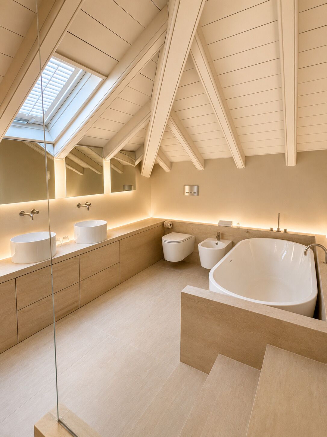 A modern bathroom with skylights, a freestanding bathtub, and a large mirror.