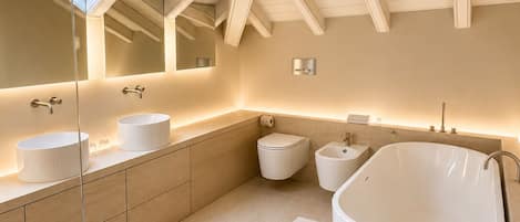 A modern bathroom with skylights, a freestanding bathtub, and a large mirror.