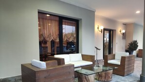 A modern lounge area with wooden furniture, a glass coffee table, and a large window with curtains. - Hotel Memory (Rimini)