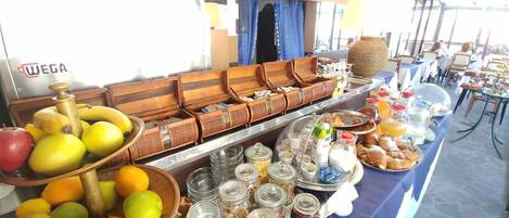 A buffet setup with various food items and beverages, including fruits, pastries, and condiments.