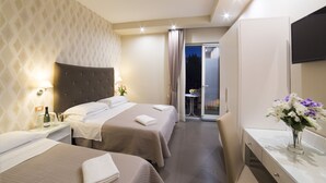 Habitación de hotel con dos camas, minibar, televisión y baño con espejo y lavamanos.