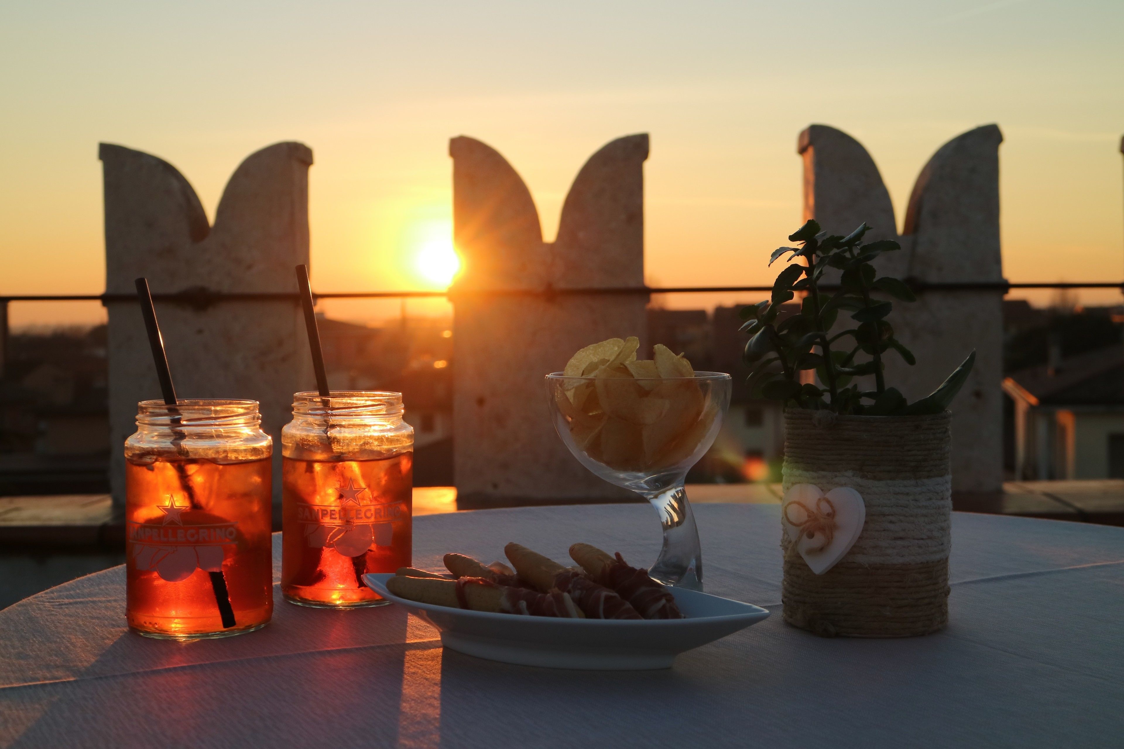 A table with two mason jars of iced tea, a bowl of fries, and a plant in a woven pot.