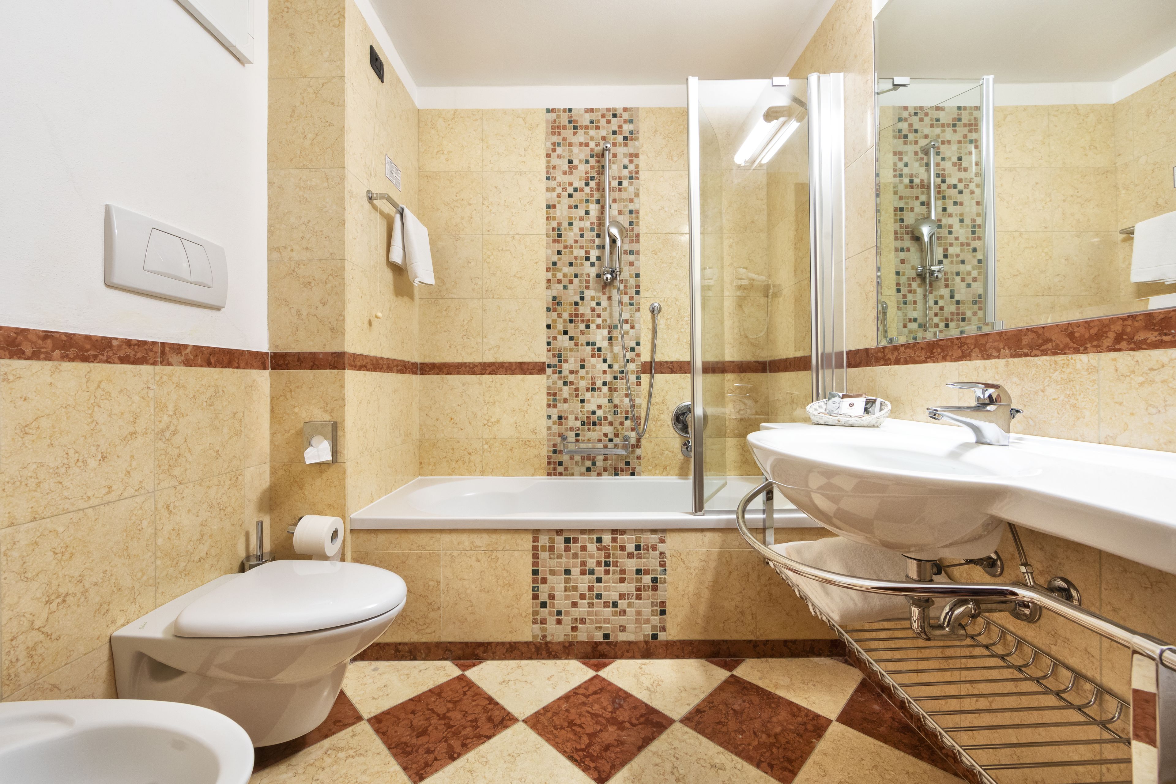 A bathroom with a toilet, bidet, shower, and sink.