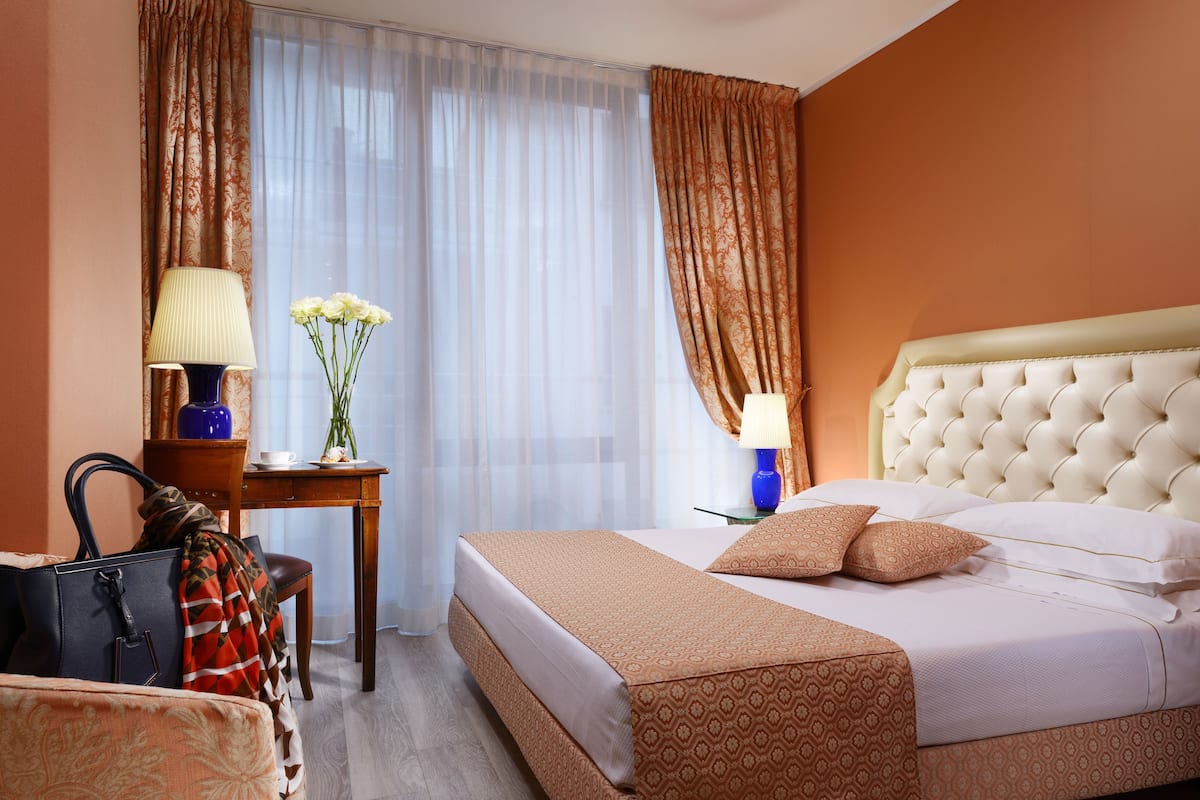 Ein Hotelzimmer mit Bett, Schreibtisch, Stuhl und Lampe.