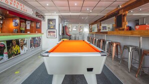 Una mesa de billar en un área de bar con taburetes y un cartel que dice 'LEGENDS SPORTS BAR'.