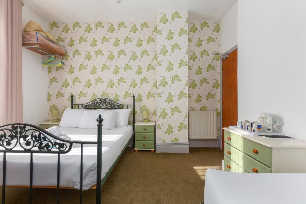 Un dormitorio con cama, mesita de noche, cómoda y radiador.