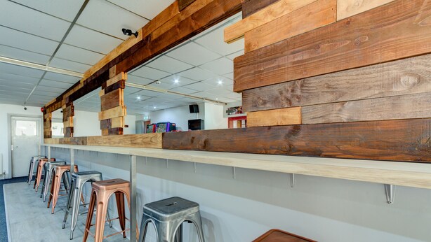 Una barra larga con paneles de madera y varios taburetes.