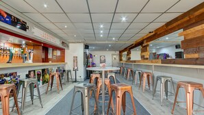 Zona de bar con varios taburetes y una barra, con una exhibición de recuerdos deportivos y una pared de acento de madera.