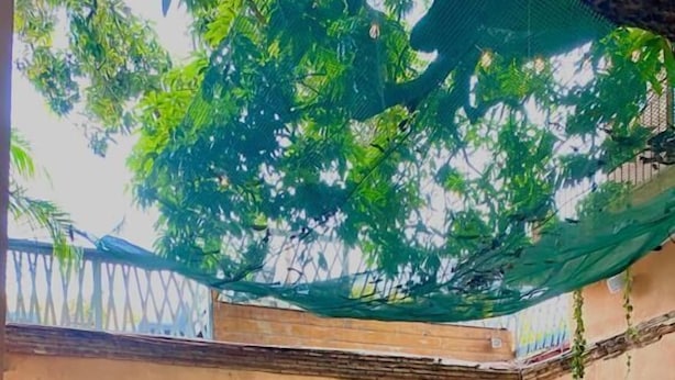 Un patio con piscina, suelo de piedra y una zona de estar cubierta con mesas y sillas.