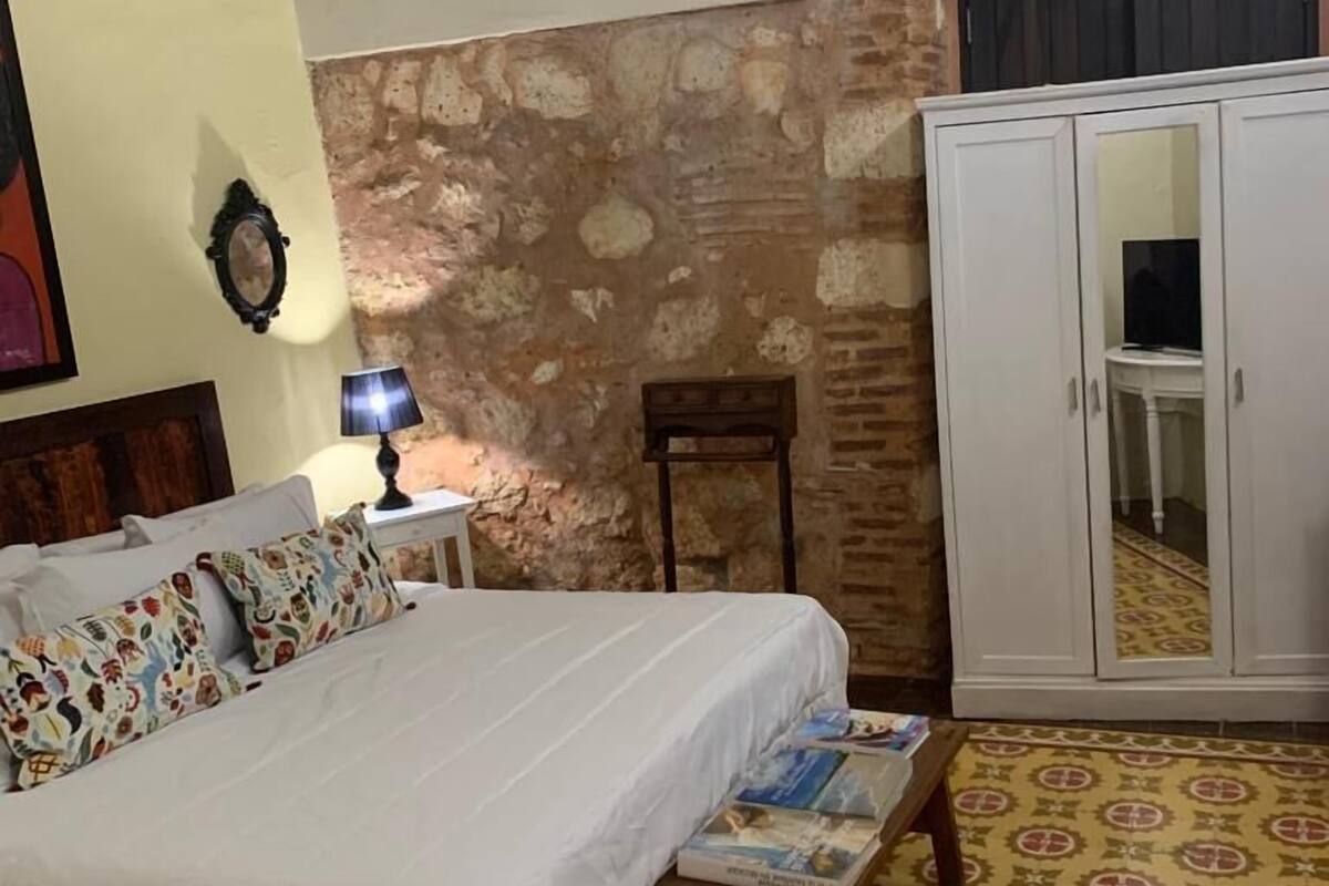 Ein Schlafzimmer mit einem Bett, einem Nachttisch, einer Lampe, einem Kleiderschrank und einem gemusterten Boden.