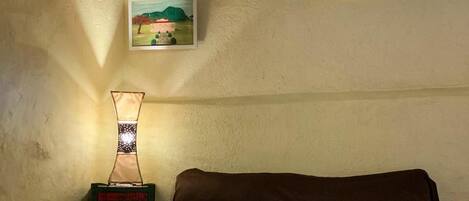 Un dormitorio con una cama, una mesita de noche, una lámpara y un cuadro en la pared.