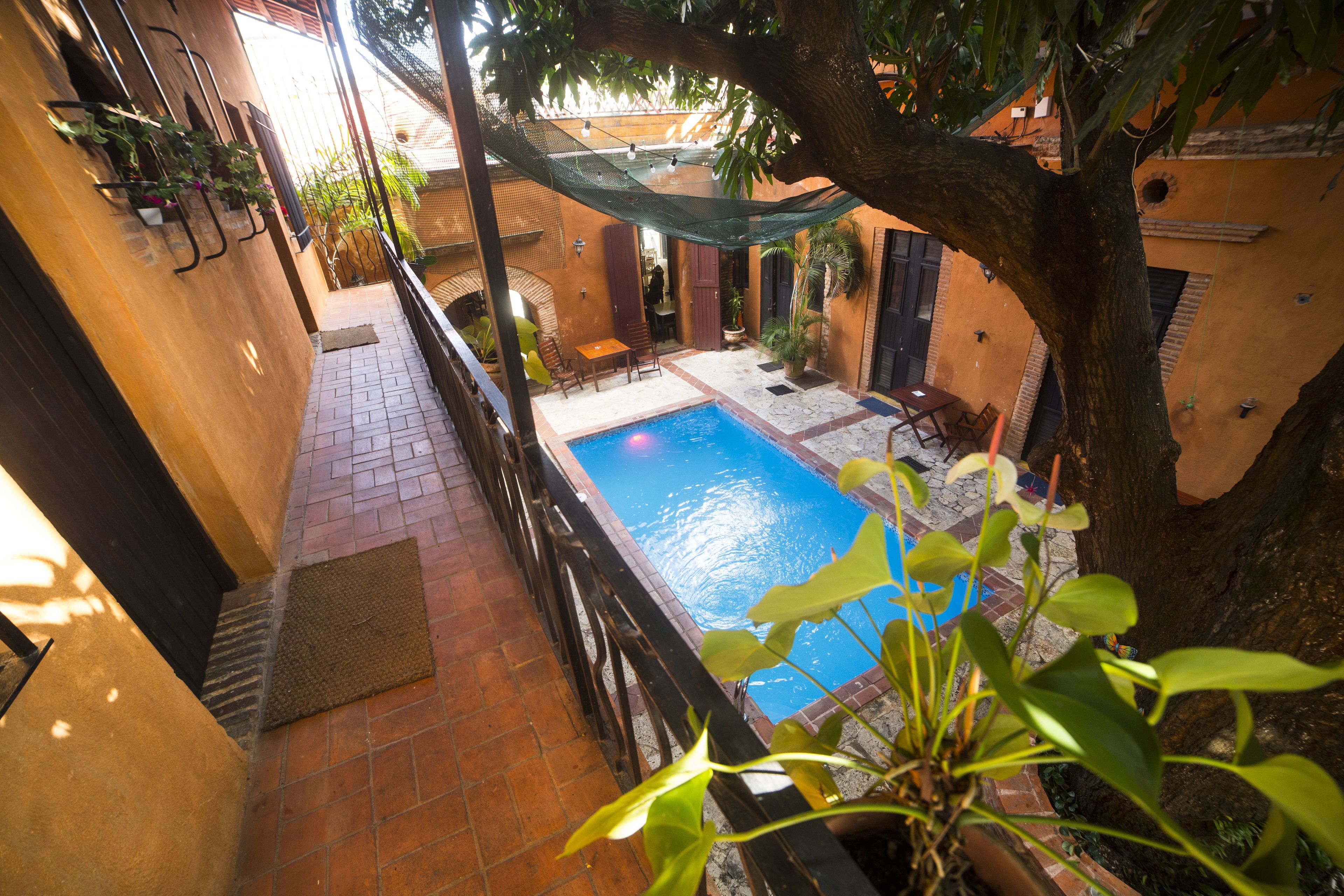 A courtyard with a swimming pool, a hammock, and potted plants.