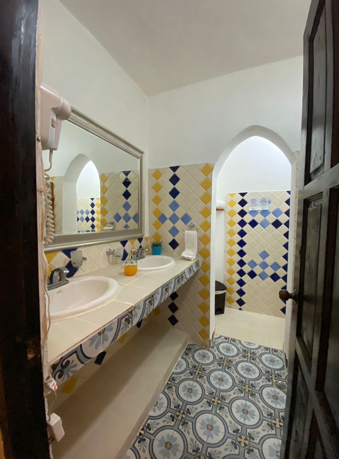 Un bagno con due lavandini, uno specchio e piastrelle decorate.