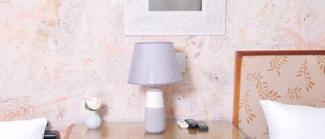Une chambre avec deux lits, une table de chevet avec une lampe, un tableau encadré et un mur décoratif.
