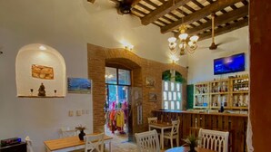 Un comedor con una mesa de madera y sillas blancas, una pared de ladrillo y una barra con estantes llenos de botellas.