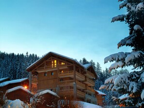 A multi-story wooden lodge with balconies, surrounded by snow-covered trees. - CGH Résidences & Spas L'Oree des Cimes (Landry)