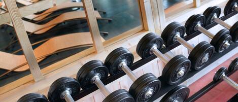 A rack of black dumbbells with silver handles, arranged on a wooden shelf.
