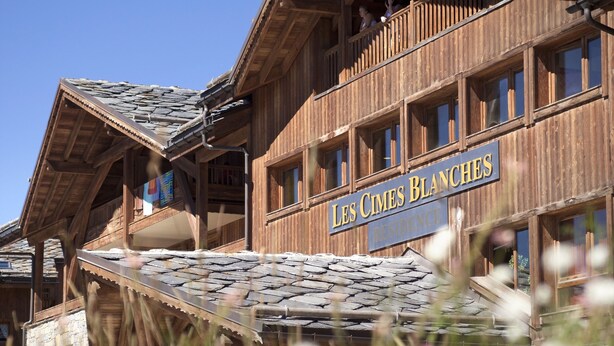 A wooden building with balconies and a sign reading "Les Cimes Blanches."