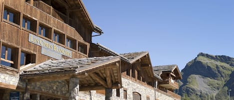 A wooden building with balconies and stone walls, named "Les Cimes Blancs".