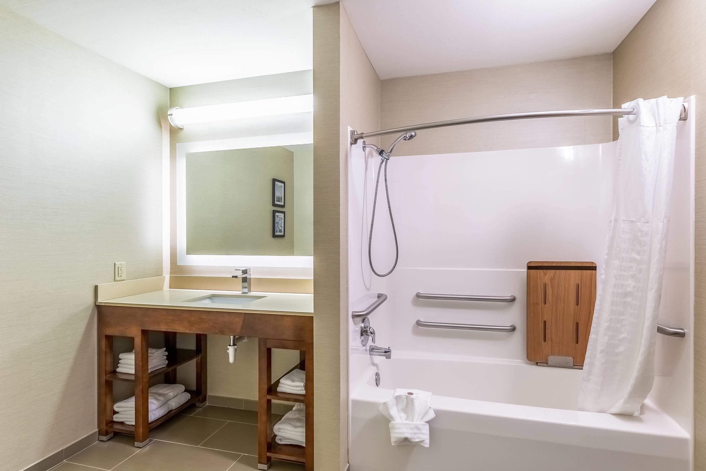 Baño con lavamanos, espejo, toallero y zona de ducha.