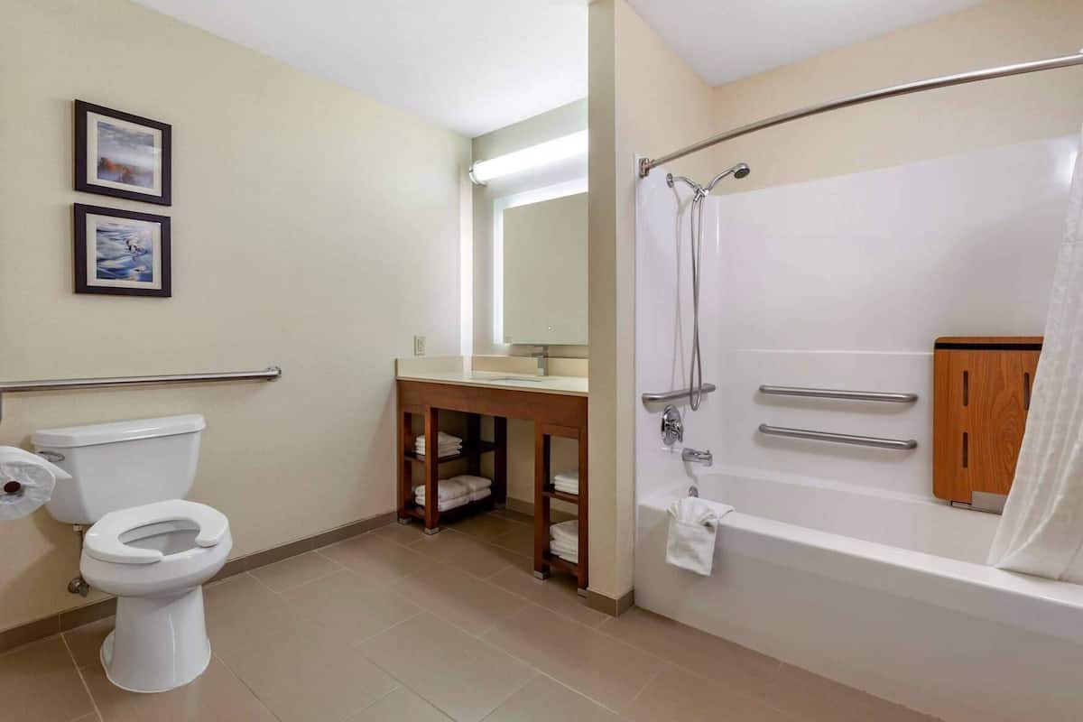 Ein Badezimmer mit Toilette, Waschbecken, Spiegel, Dusche und Handtuchhalter.