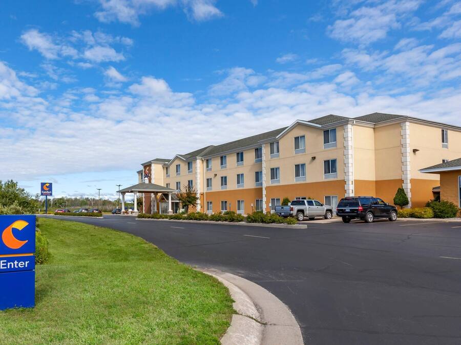 Un hôtel doté d’un parking, d’une enseigne indiquant qu’il s’agit d’un hôtel Comfort Inn, et un ciel dégagé.
