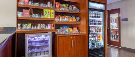 Een kitchenette met een koelkast, een magnetron en een koffieapparaat.