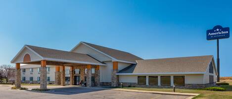 A hotel with a covered entrance, multiple windows, and a sign indicating it is an AmericInn by Wyndham.